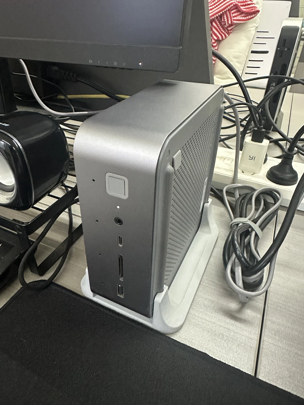Beelink GTi13 竖立放在浅灰色 3D 打印支架中,已经安装在桌面上